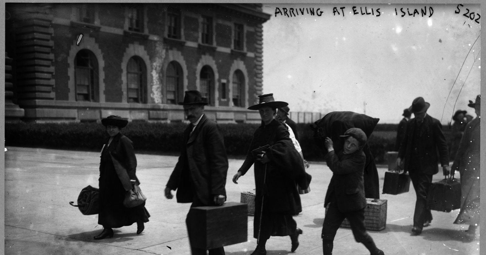 Grupa imigrantów z bagażami przybywających na wyspę Ellis w Nowym Jorku, fotografia archiwalna.