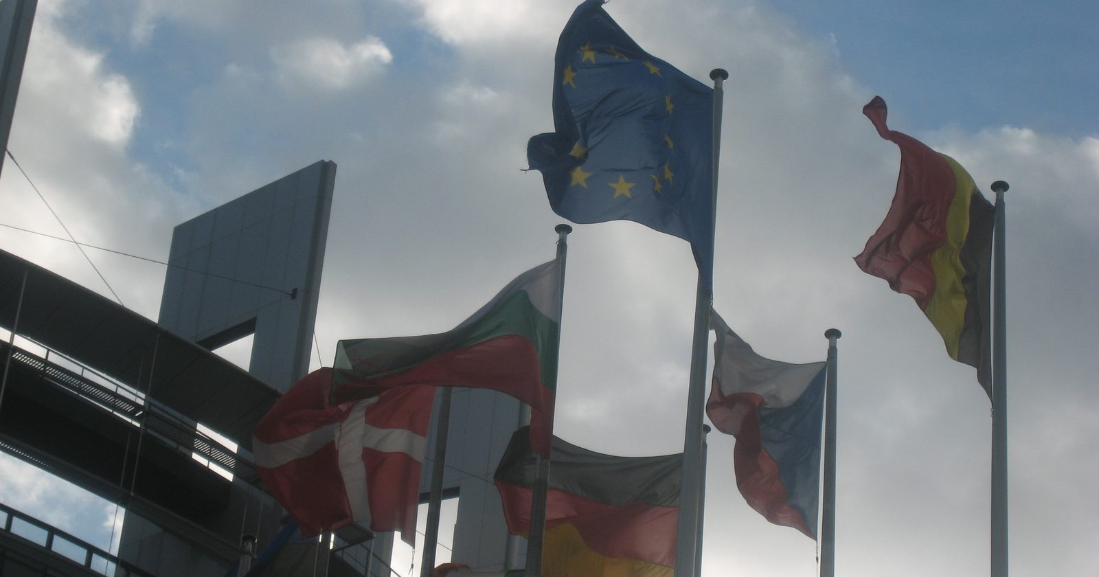 Flagi państw członkowskich przed budynkiem Louise Weiss — siedzibą Parlamentu Europejskiego w Strasburgu.